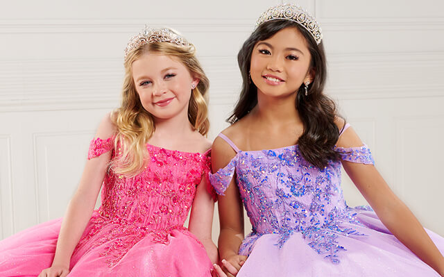 Two girls in pageant dresses holding hands
